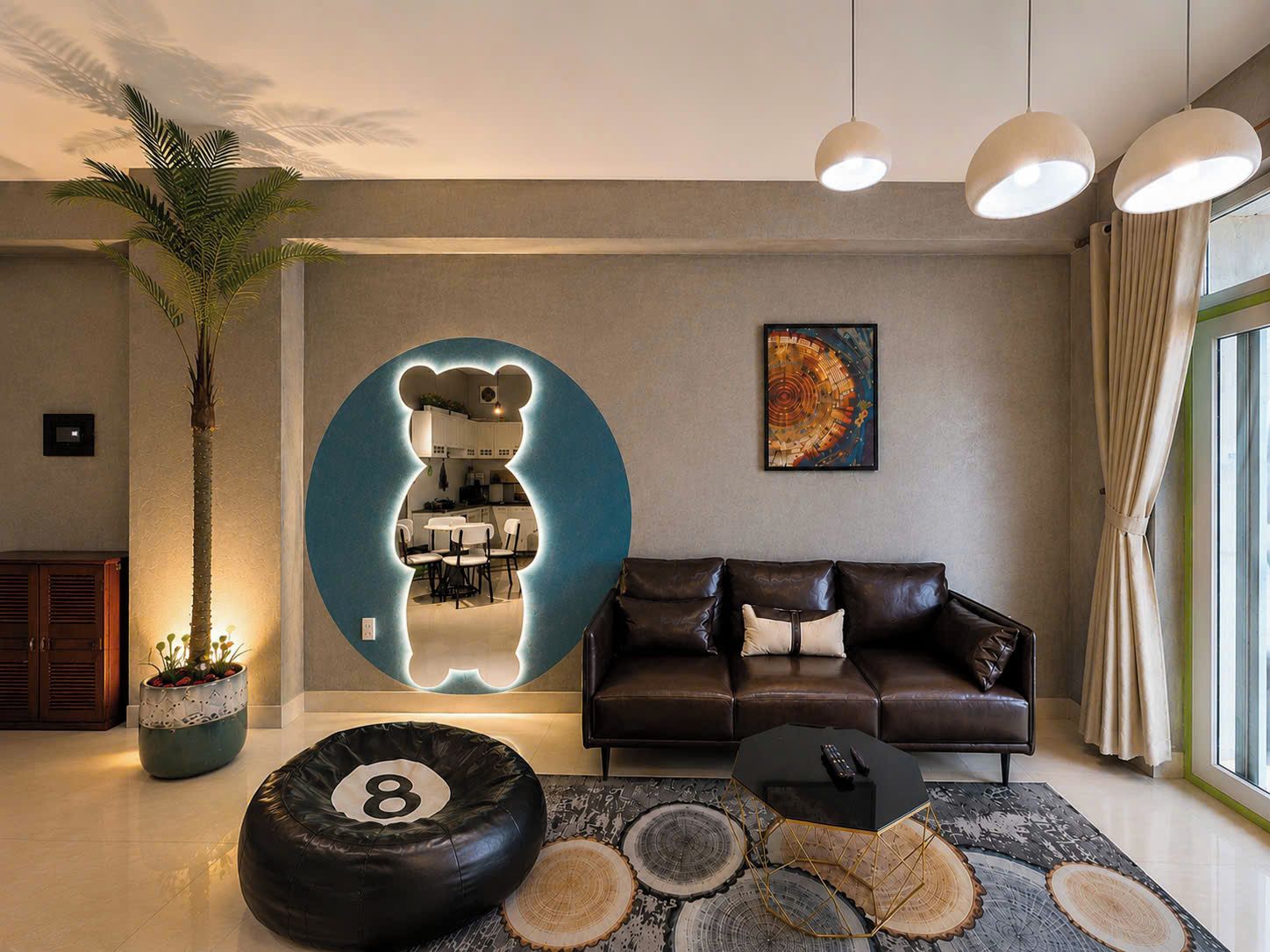 A modern living room with a sofa, a coffee table, a bear-shaped mirror, a potted plant, and a large window.