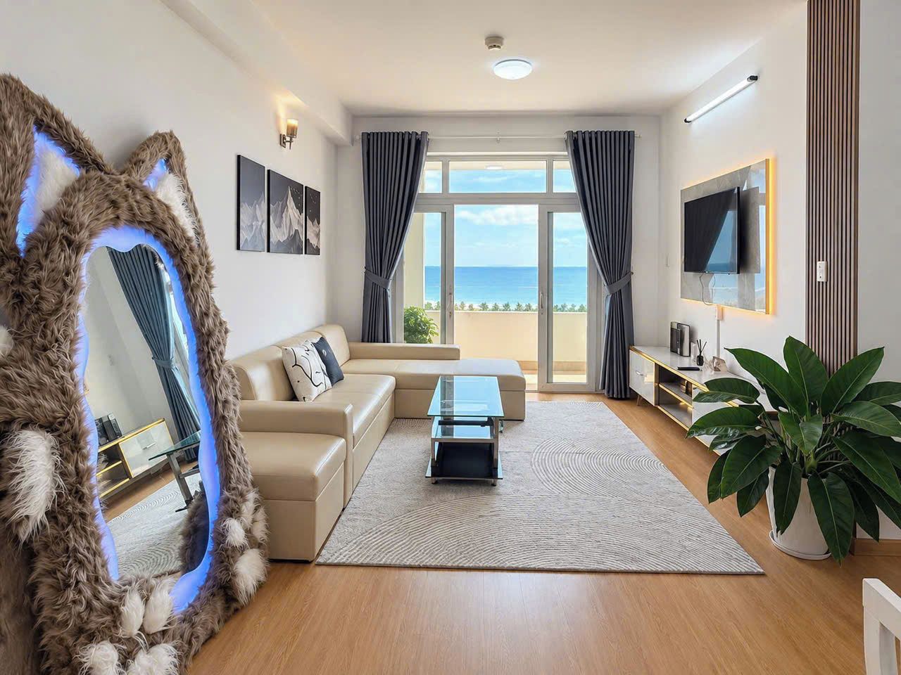 A modern living room with a sofa, a coffee table, a TV, and a large window with curtains.