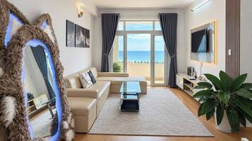 A modern living room with a sofa, a coffee table, a TV, and a large window with curtains.
