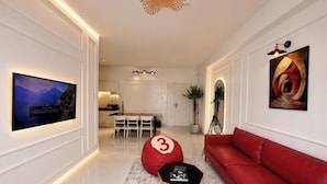 A modern living room with a red sofa, a black coffee table, and a large TV mounted on the wall. - MOC AN COLLECTION-Blue Sea Beachfront VT (Vung Tau)