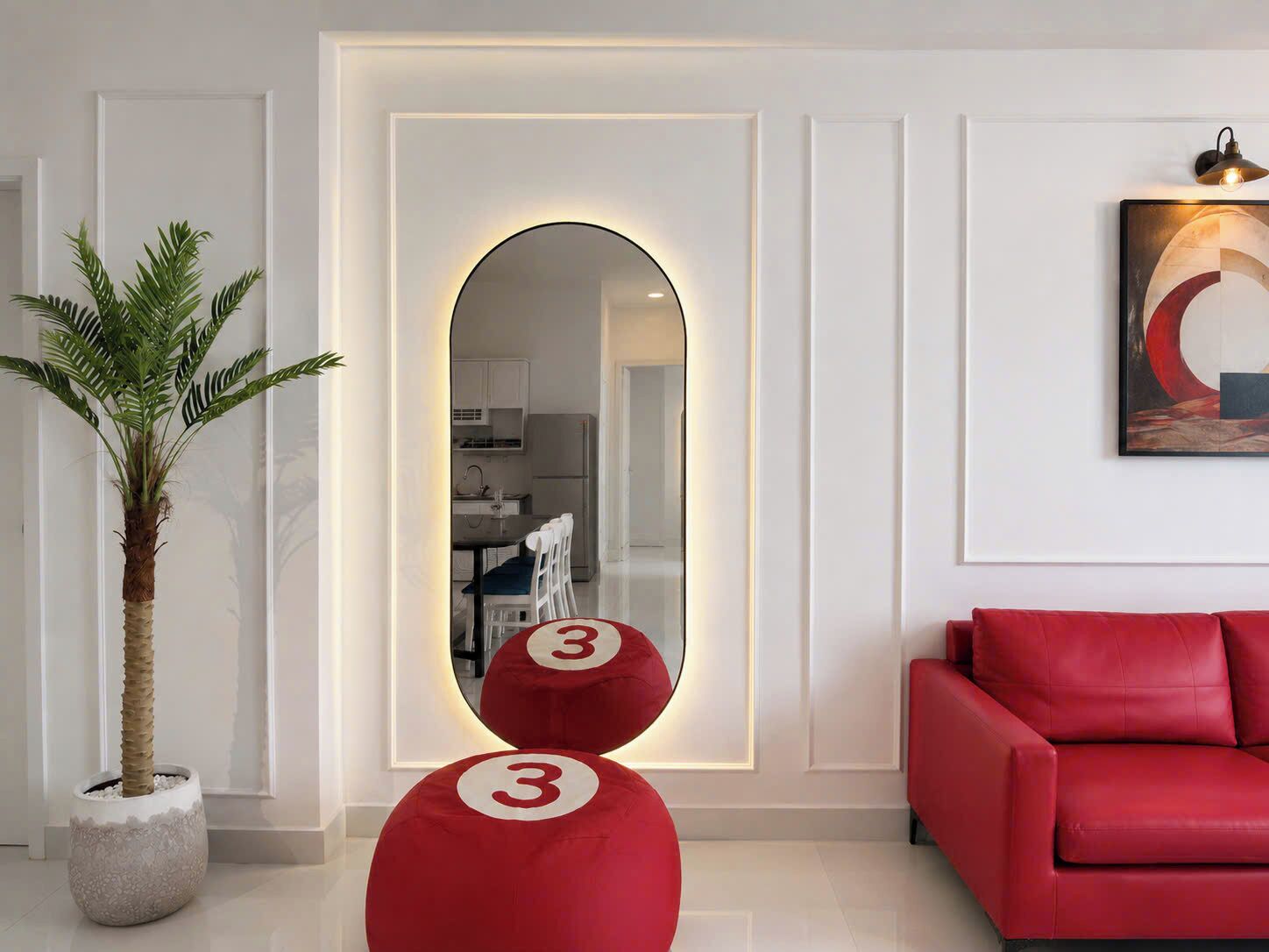 Uma sala de estar moderna com um sofá vermelho, uma planta em vaso e um espelho com moldura circular.