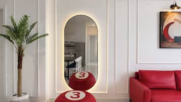 A modern living room with a red sofa, a potted plant, and a mirror with a circular frame.