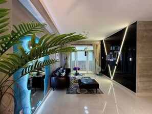 A modern living room with a sofa, a coffee table, and a large potted plant. - MOC AN COLLECTION-Blue Sea Beachfront VT (Vung Tau)