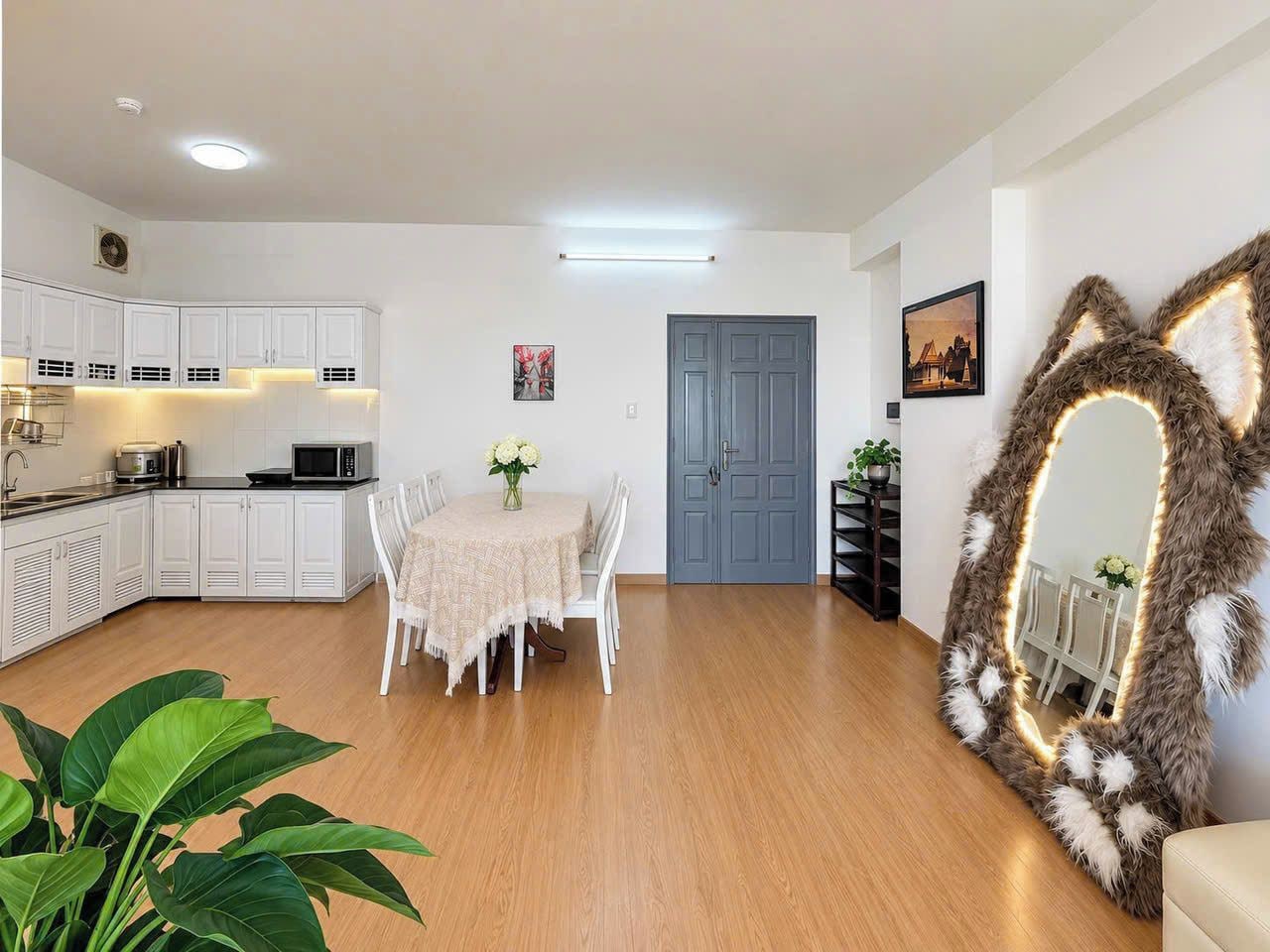A modern living room with a dining area, kitchen, and a large mirror with a furry frame.