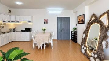 A modern living room with a dining area, kitchen, and a large mirror with a furry frame.
