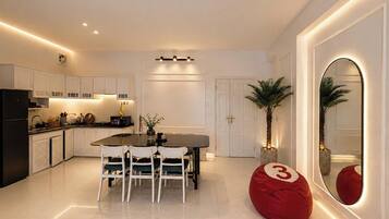 A modern kitchen with white cabinetry, a dining table with chairs, a red bean bag, and a large mirror with a number '3' on it.