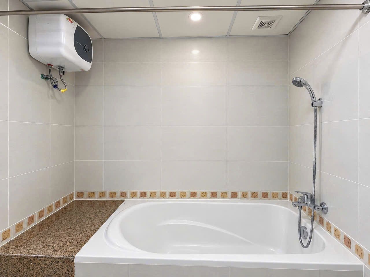 A bathroom with a bathtub, a shower, and a hand dryer mounted on the wall.