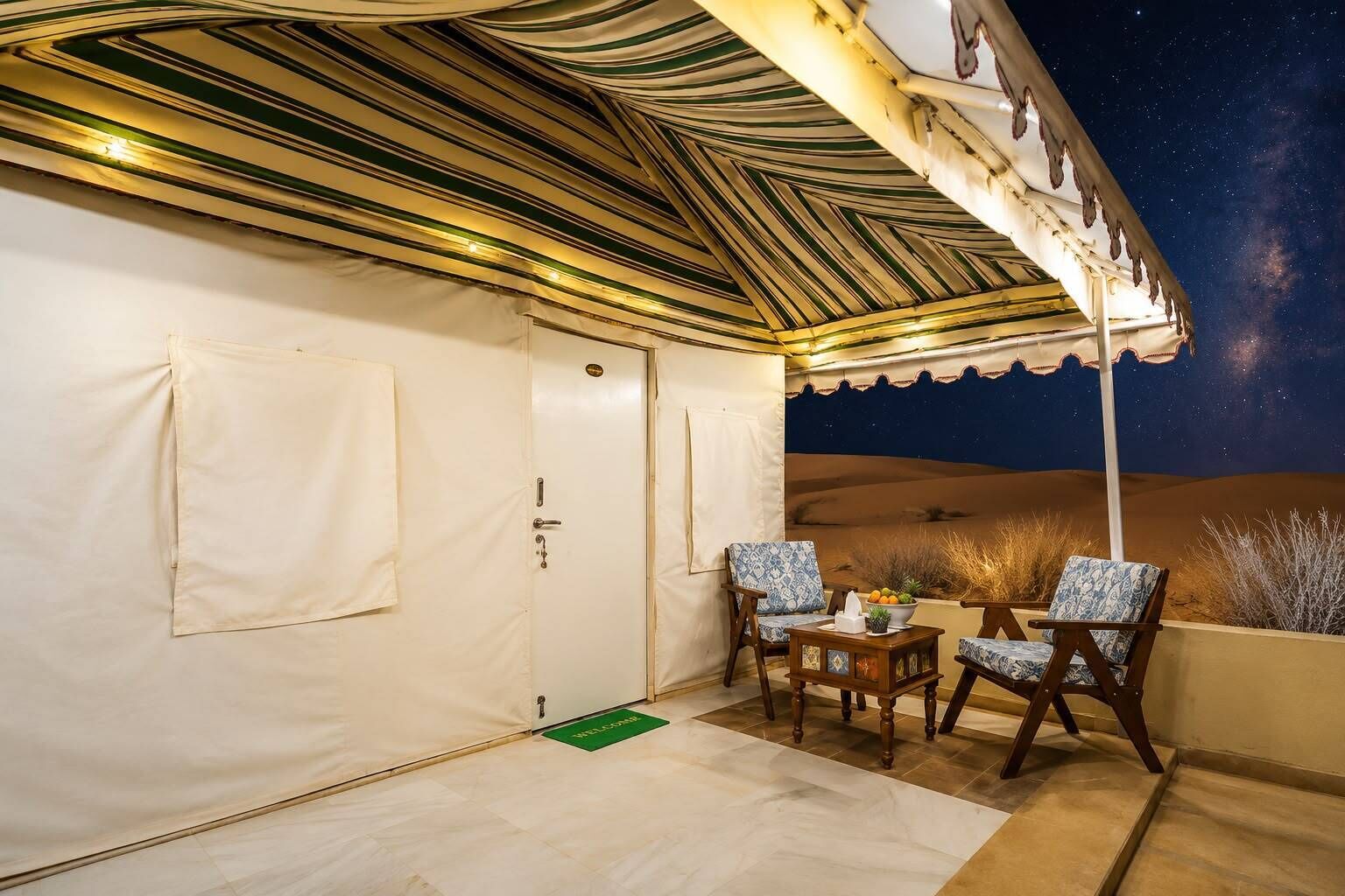 A desert-themed room with a canopy, two chairs, a small table, and a door.