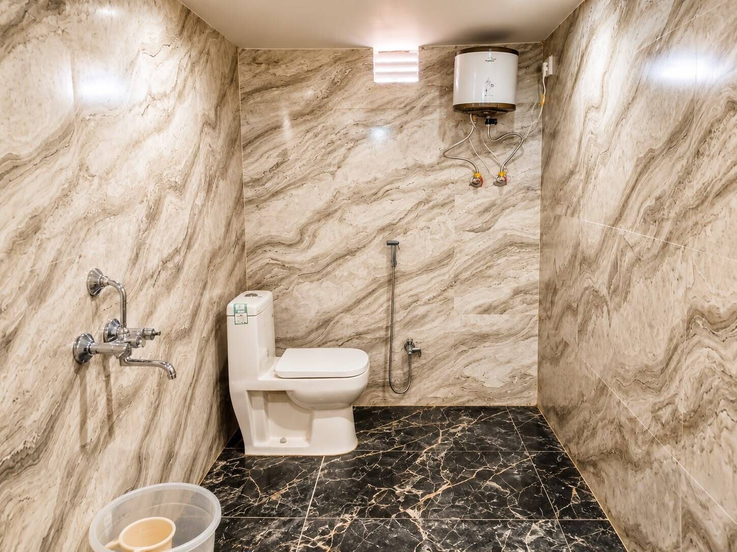 A bathroom with a marble wall, a toilet, a shower, and a water heater.