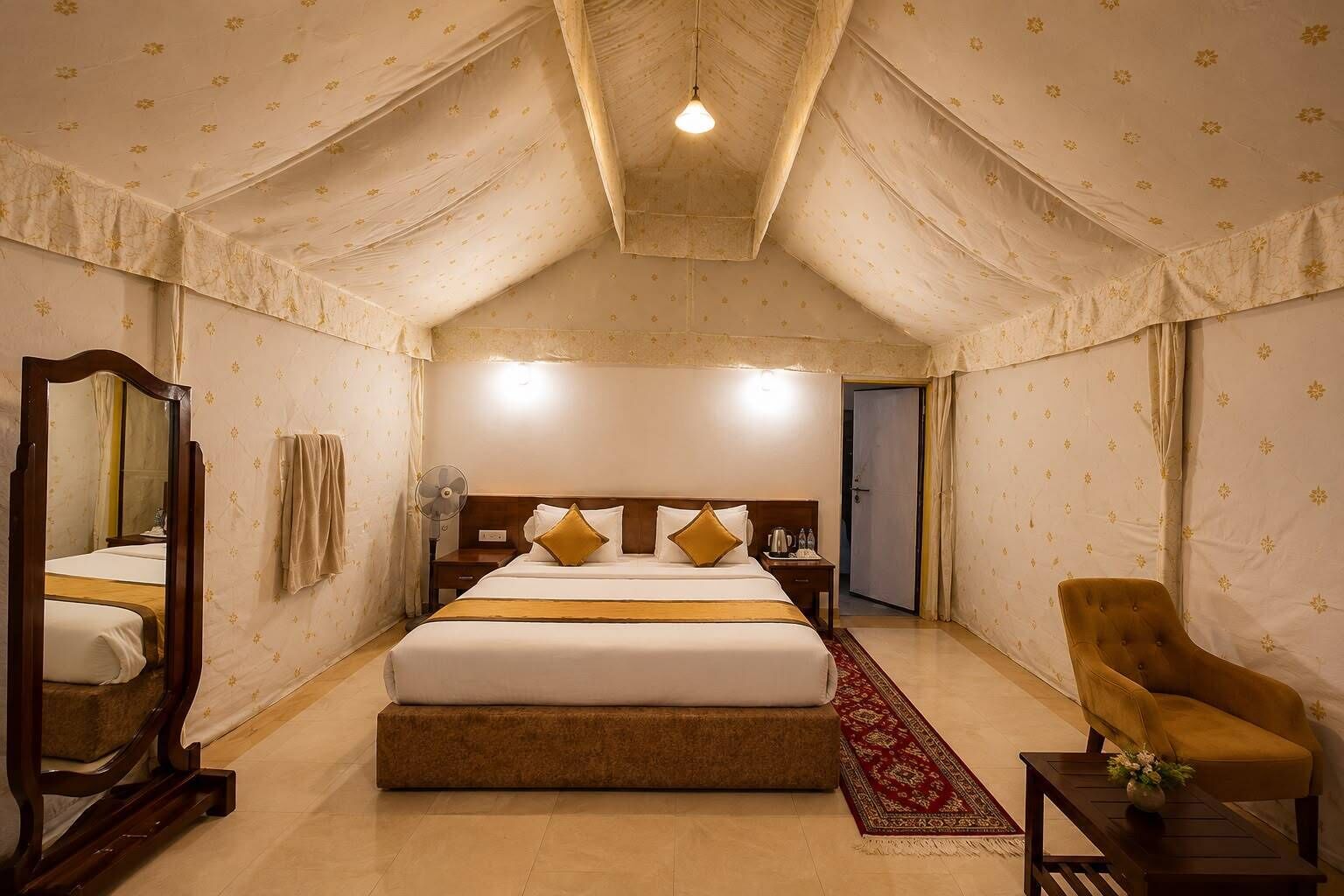 A bedroom with a large bed, a wooden nightstand, a bedside table, a chair, a mirror, and a door.