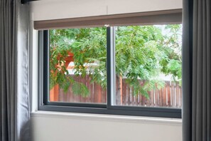 A window with a view of a wooden fence and green foliage.
