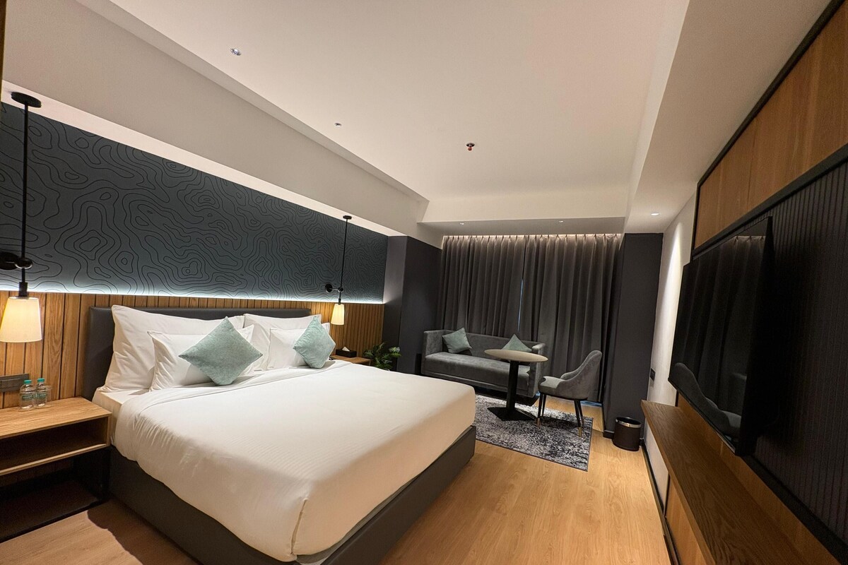 Una habitación de hotel moderna con una cama grande, un sofá, un televisor y un escritorio.