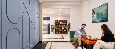Una sala de estar moderna con una mesa de ajedrez, un sofá verde y una estantería.