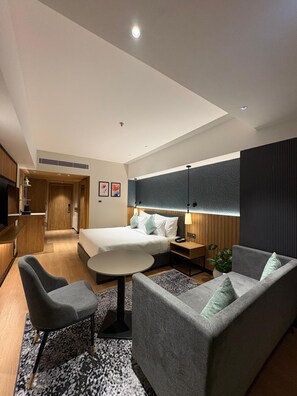 Una habitación de hotel moderna con una cama, un sofá, un escritorio y un televisor.