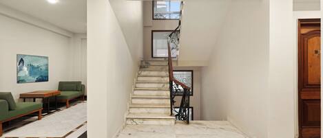 A modern interior with a marble staircase, a green sofa, and a wooden door.