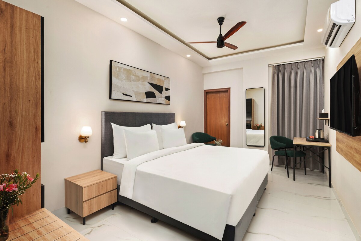 A hotel room with a bed, bedside table, nightstand, desk, chair, and a ceiling fan.