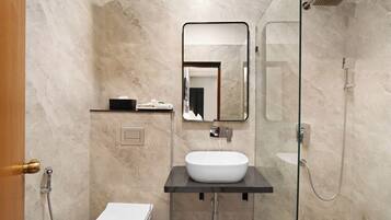 Un baño moderno con un lavamanos blanco, un espejo, una ducha y un inodoro.