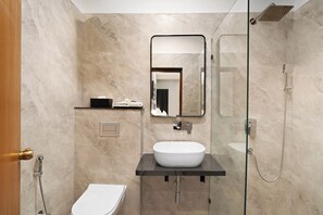 A modern bathroom with a white sink, a mirror, a shower, and a toilet. - Country Inn Smart Stays Gurgaon (Gurugram)
