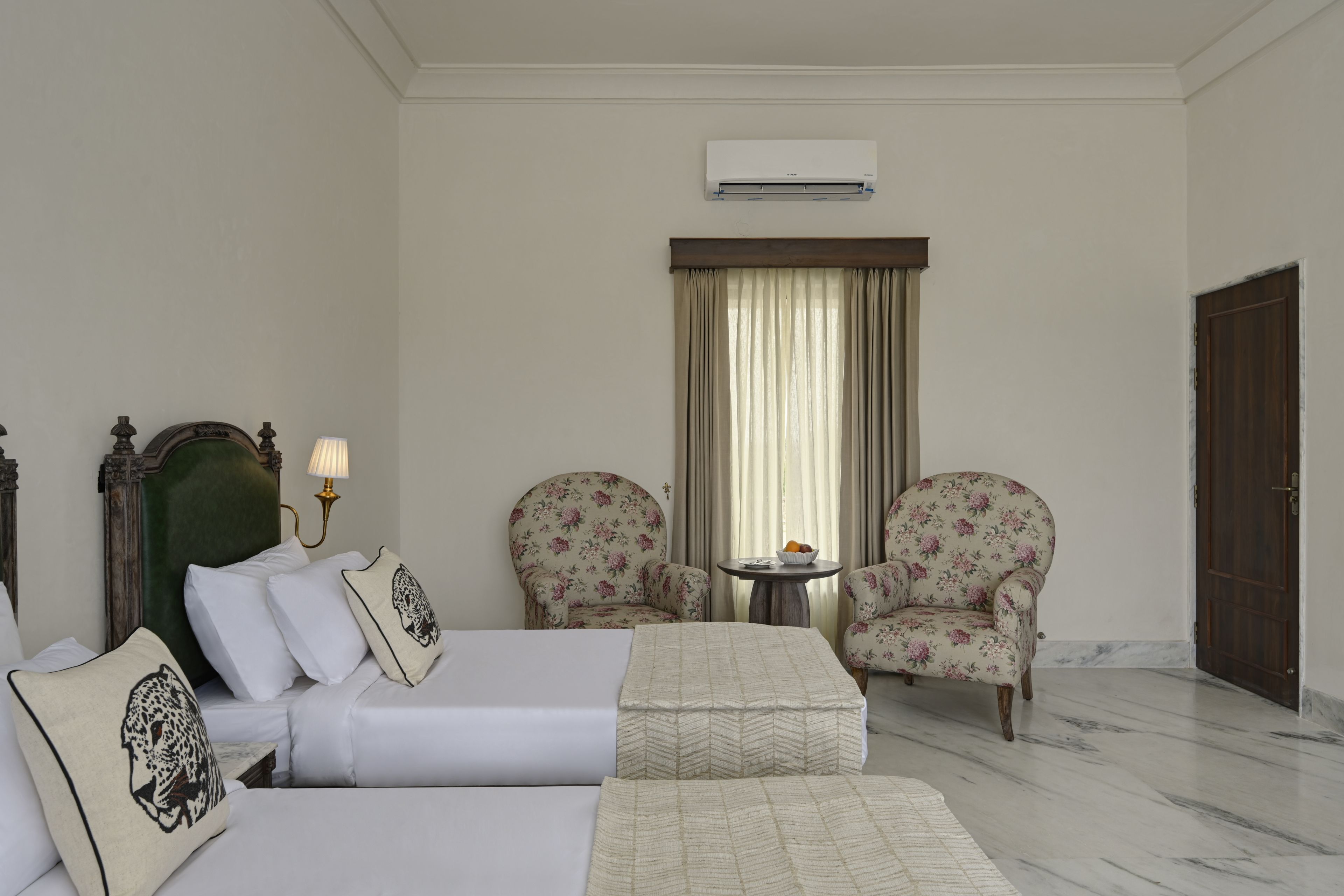 A hotel room with a bed, two armchairs, a small table, and a door.
