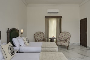 A hotel room with a bed, two armchairs, a small table, and a door.