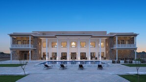 A large, two-story building with a central courtyard, a swimming pool, and outdoor seating. - Hari Bagh Jawai (Bali)