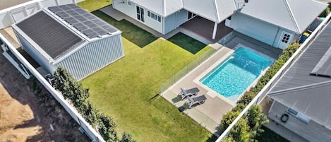 A residential property with a swimming pool, solar panels, and a fenced yard.