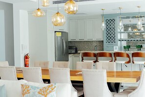 A modern kitchen with white cabinets, a stainless steel refrigerator, and a dining area with a wooden table and chairs. - 
4BR VIP Villa with Private Pool, Gold band, Chef & Golf Cart, Puerto Plata, DR (Puerto Plata)
