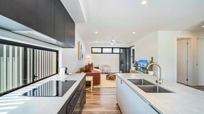 A modern kitchen with a central island, a dining area with a sofa and table, and a view of a mountainous landscape through a large window.