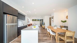 Une cuisine moderne dotée d’un îlot central, d’appareils électroménagers en acier inoxydable et d’un coin repas avec des meubles en bois.