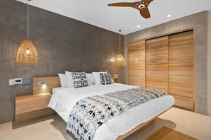 Ein modernes Schlafzimmer mit einem großen Bett, Nachttischlampen, einem Holzschrank und einem Deckenventilator.