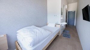 Un dormitorio moderno con una cama individual, mesita de noche y un escritorio pequeño.