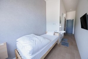 A modern bedroom with a single bed, bedside table, and a small desk. - SSBHOTELSOUROU (Satsumasendai)