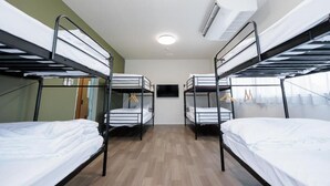 Una habitación con literas, un televisor de pantalla plana y un equipo de aire acondicionado.