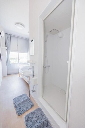 A modern bathroom with a glass-enclosed shower, a white sink, and a large window. - SSBHOTELSOUROU (Satsumasendai)