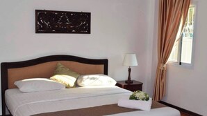 Ein ordentlich bezogenes Bett mit braunem Kopfteil, ein Nachttisch mit Lampe und eine dekorative Wandgestaltung.