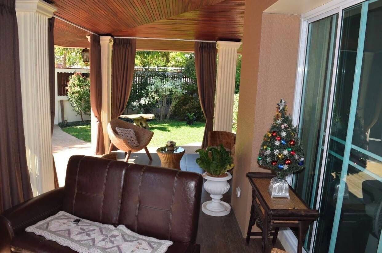 Ein überdachter Patio-Bereich mit einer Ledersofa, einem kleinen Tisch, einem Topfpflanzen und einem Weihnachtsbaum.