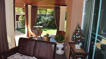 Ein überdachter Patio-Bereich mit einer Ledersofa, einem kleinen Tisch, einem Topfpflanzen und einem Weihnachtsbaum.