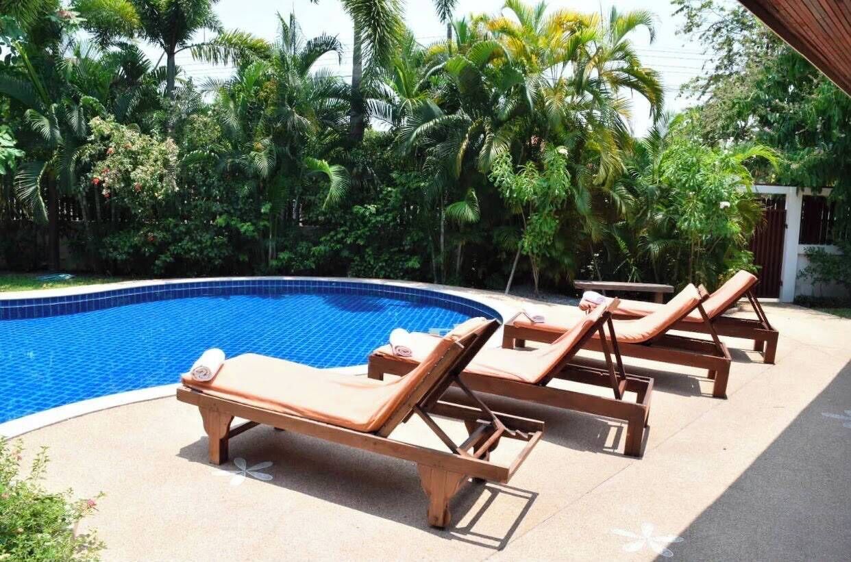 A swimming pool with lounge chairs and tropical vegetation.