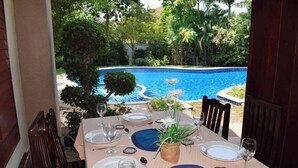 Ein Esstisch mit Blick auf einen Pool und Grünflächen.