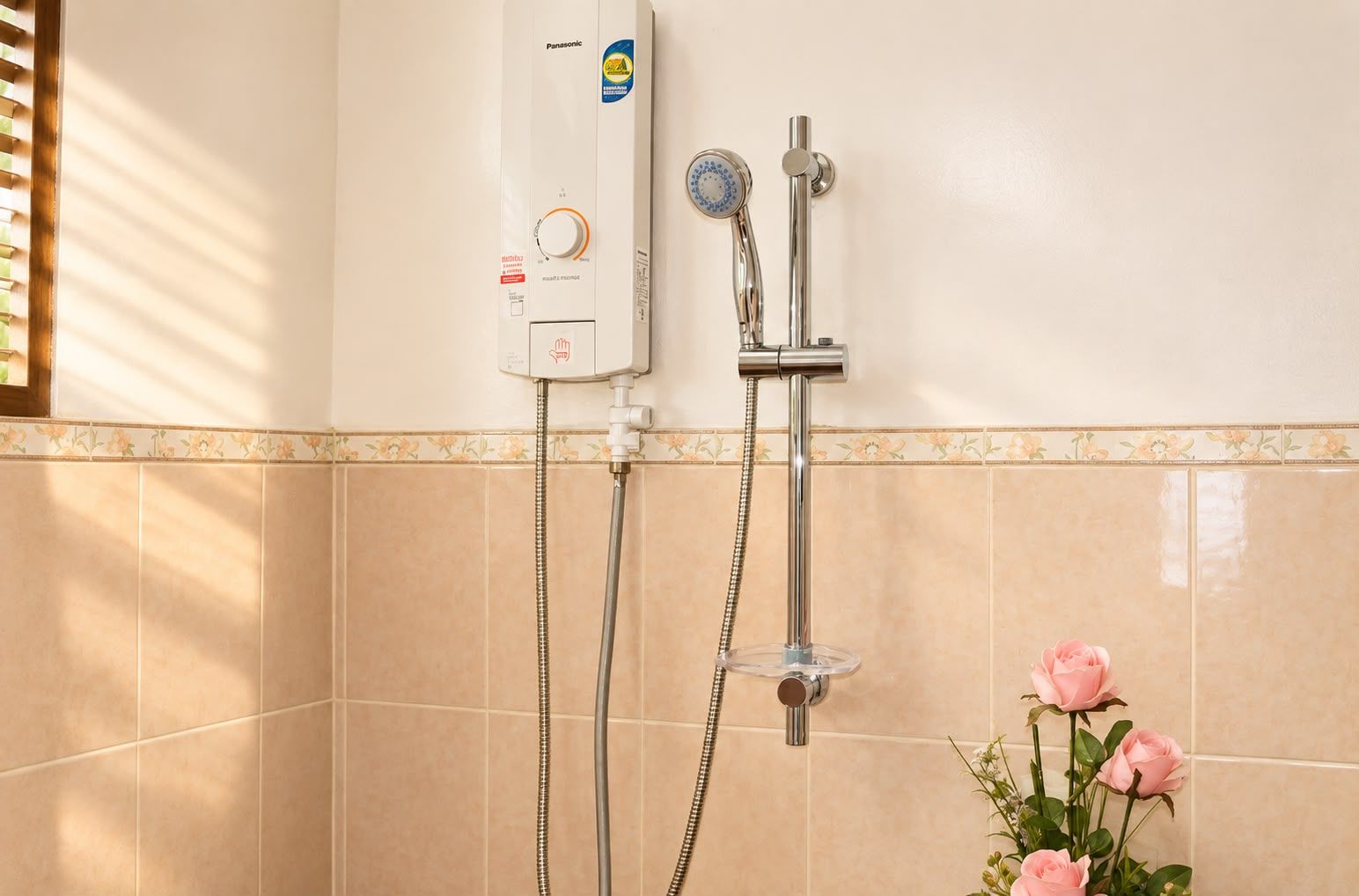 Un baño con ducha empotrada, panel de control y un florero con rosas.