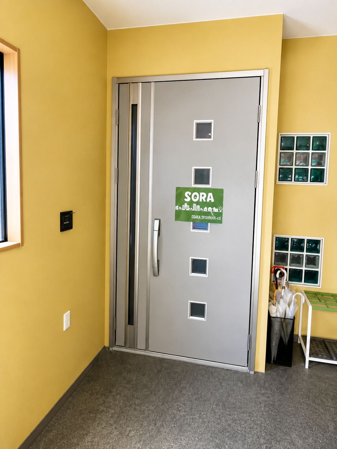 A door with a sign reading 'SORA' and a small window with a towel rack.
