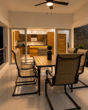 A modern kitchen with a dining area, featuring a wooden table and chairs, a ceiling fan, and a view into the adjacent living space. - Room-villa With Pool Near Laguna Gri-grí (Rio San Juan)