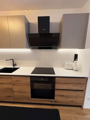 A modern kitchen with a built-in oven, a dishwasher, and a black range hood.