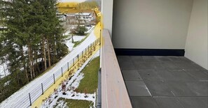 Parveke, jolta avautuu näkymä lumipeitteiselle maisemalle, ja taustalla näkyy aita sekä rakennus.