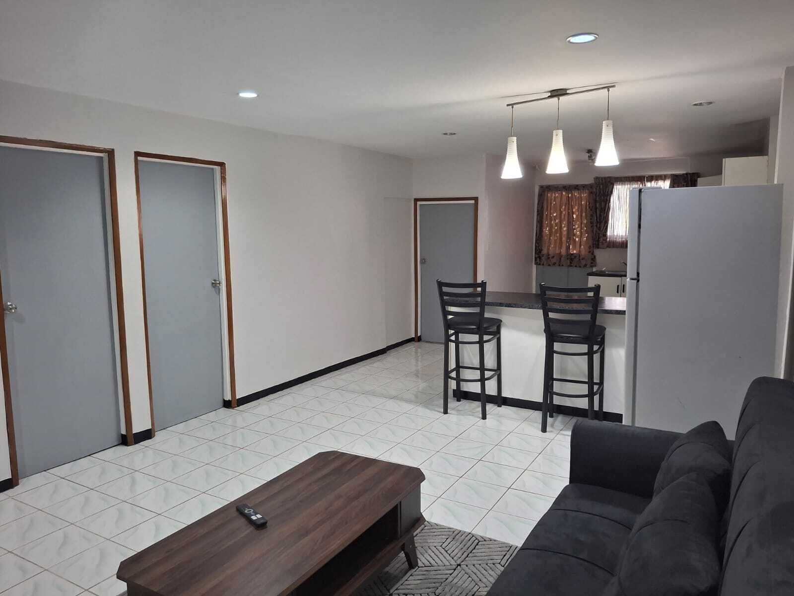 Una sala moderna con un sofá, una mesa de centro y un comedor con dos sillas.