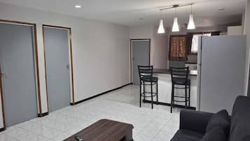 A modern living room with a sofa, a coffee table, and a dining area with two chairs.