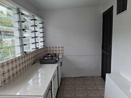Una pequeña cocina con estufa a gas, armarios blancos y baldosas estampadas.