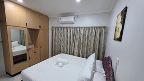 Una habitación de hotel con cama, armario, espejo, aire acondicionado y un cuadro en la pared.