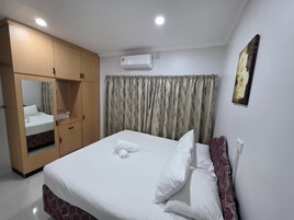 Una habitación de hotel con cama, armario, espejo, aire acondicionado y un cuadro en la pared.