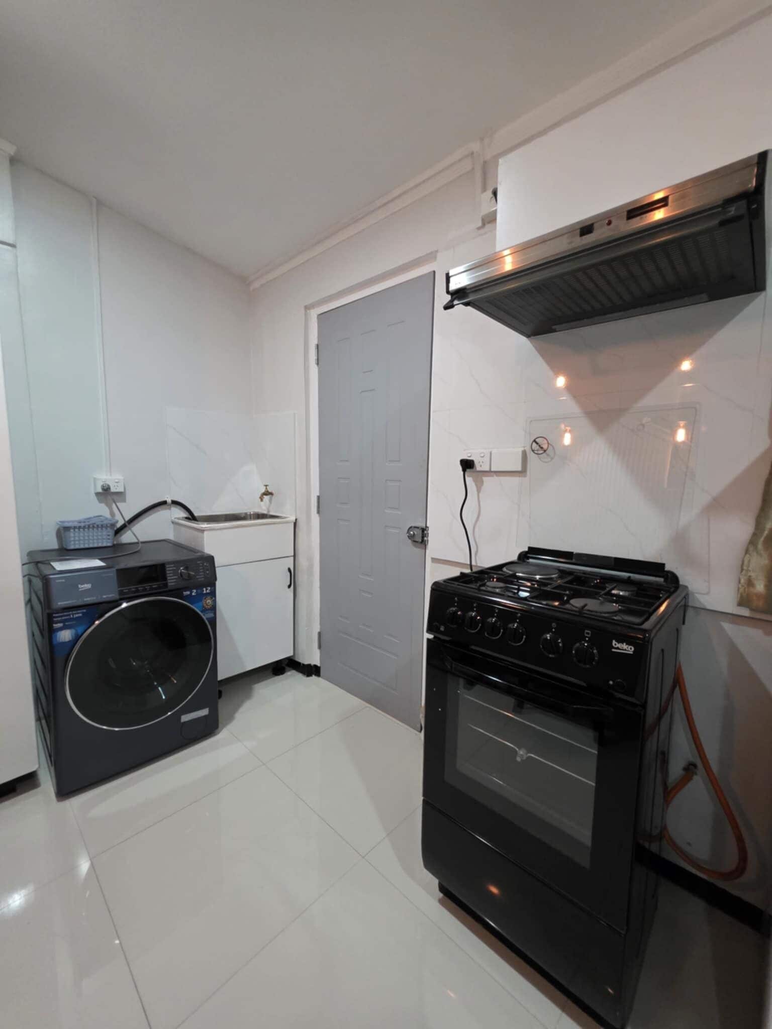Uma cozinha compacta com máquina de lavar, fogão e bancada pequena.